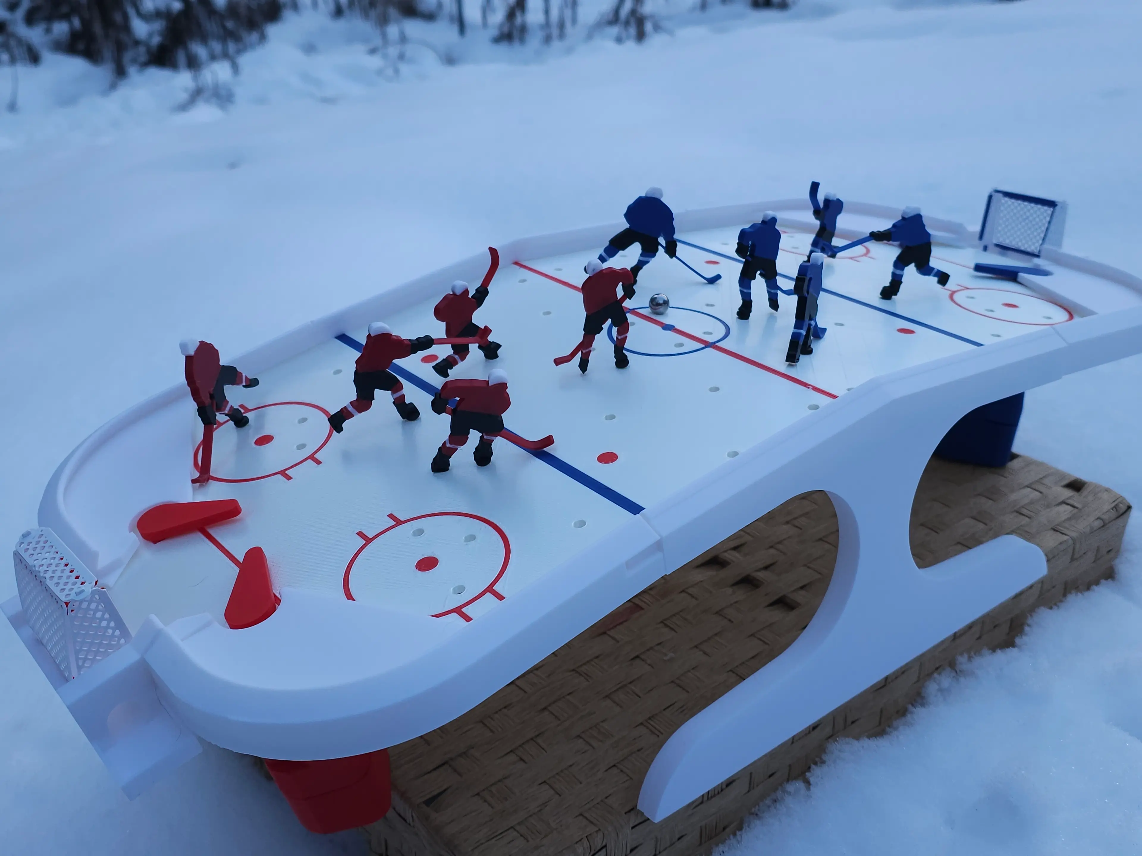 This was a super fun print! I've made a few of these desktop games for my husband to take to the fire station and am eagerly awaiting feedback!
I printed the rink with silk white PLA to give it that shiny ice look and love the way it turned out! I decided to have a little fun with an AI background but the one in snow is in our wintery yard. I was hoping for that natural light to shine up the ice rink but, it's nearly 4pm here and the sun has started to set.