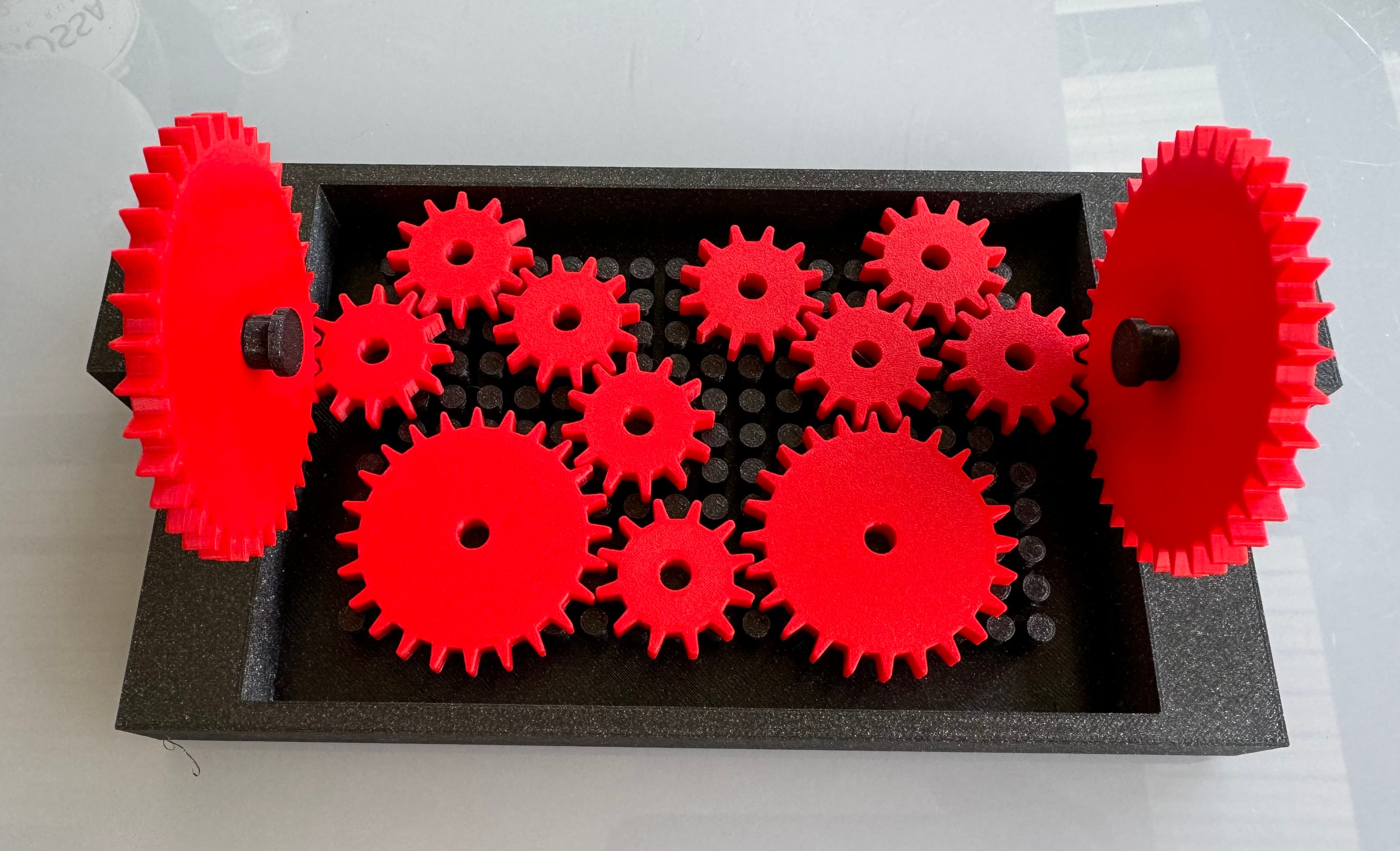 Working Solution with one useless gear (in the middle top row)
Printed with Prusament PLA (Galaxy black and Lipstick red)