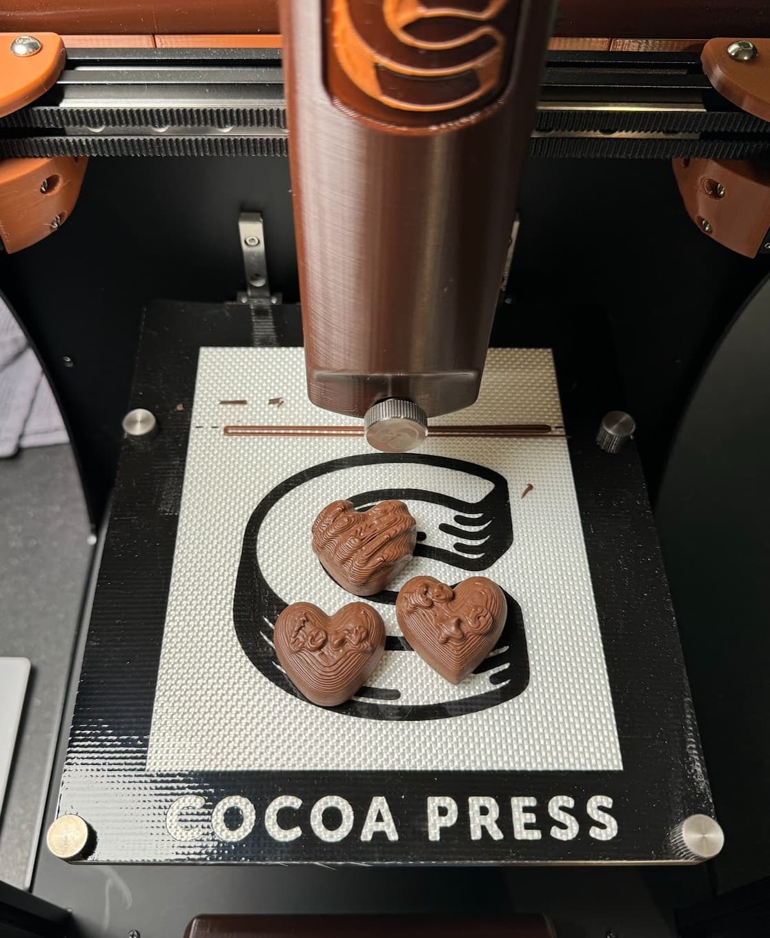 3 milk chocolate hearts on a Cocoa Press printer