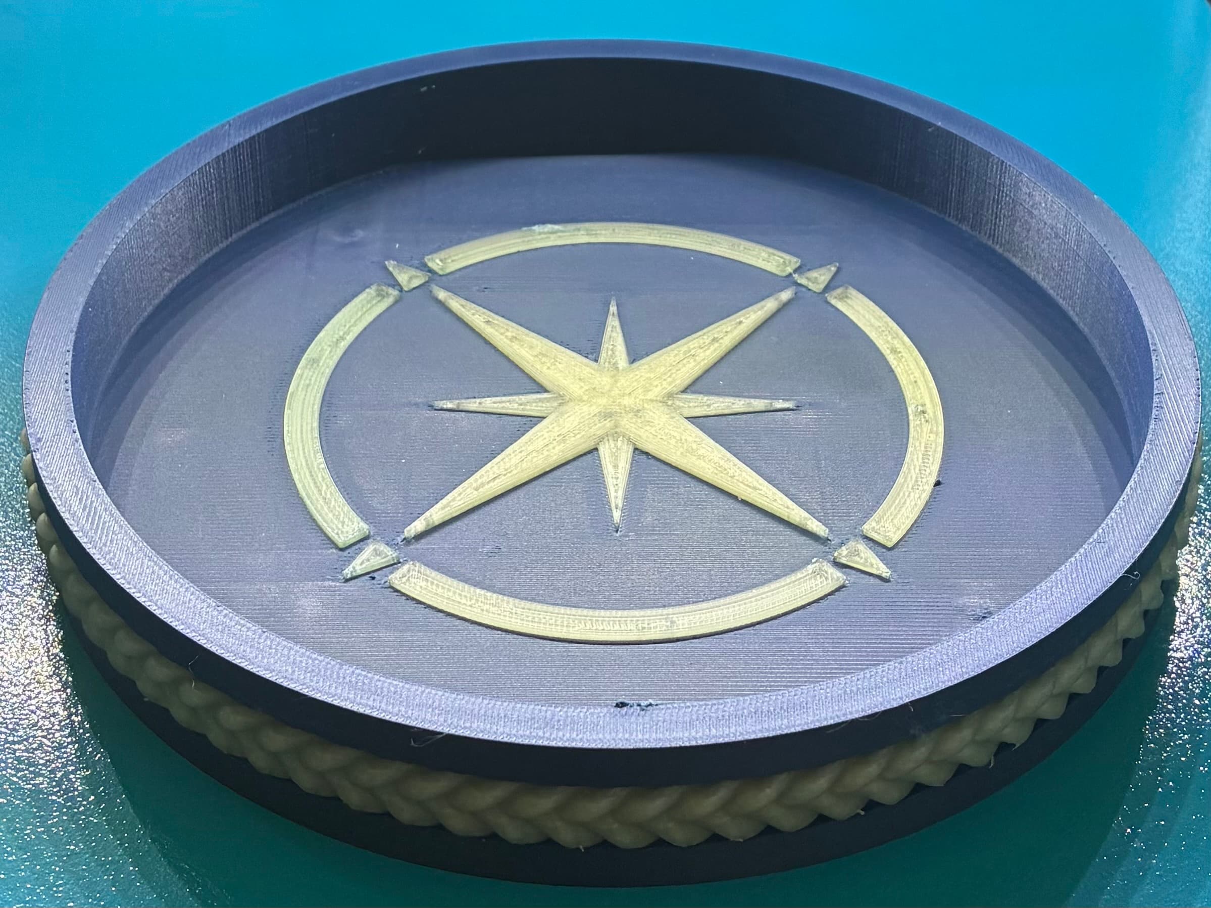 The tray came out well using BL Matte Dark Blue and BL Translucent Yellow, both in PLA. The maker's marque on the underside was a different story. Bridging after the 1 layer emboss was swept up by the repeated passes of subsequent layers, preventing model sealing that breach until the topmost compass rose layers finally succeeded. Consider a deeper emboss with enforced supports in this area.